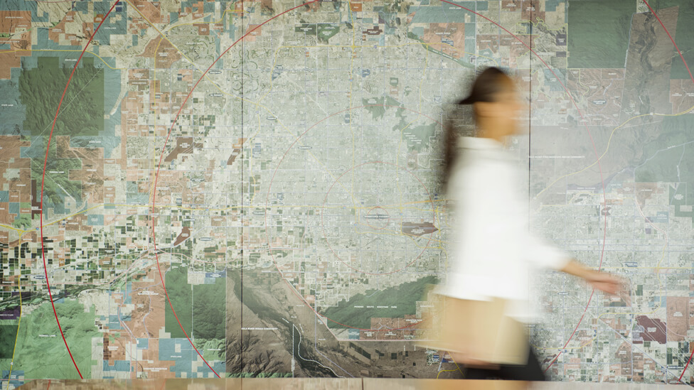 RBS, find out more On the move, a lady is blurred-in-motion as she walks past a wallmap backdrop