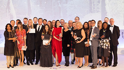 Staff in formal attire on stage displaying awards