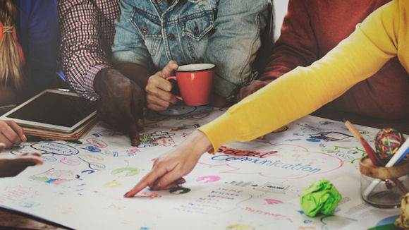 start up company employees brainstorming ideas on table with white paper and colourful markings