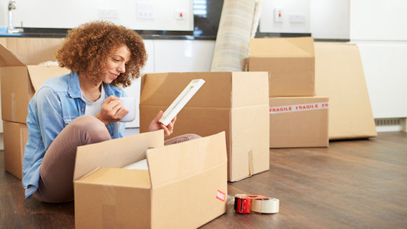 a young woman unpacking boxes in her new home after securing a mortgage